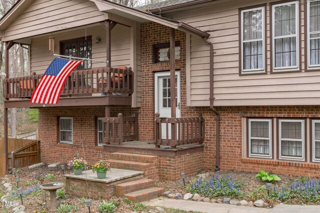 view of front of house featuring a porch, fence, and brick siding