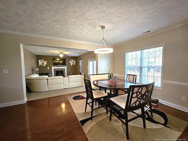 dining space featuring a textured ceiling, baseboards, visible vents, and wood finished floors