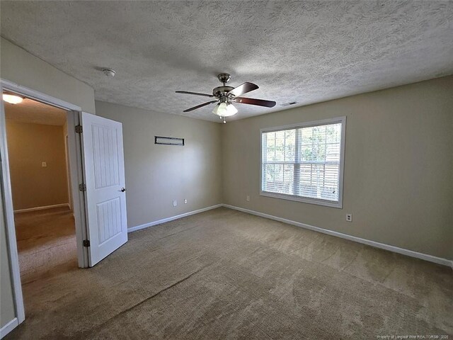 empty room with baseboards, carpet, ceiling fan, and visible vents