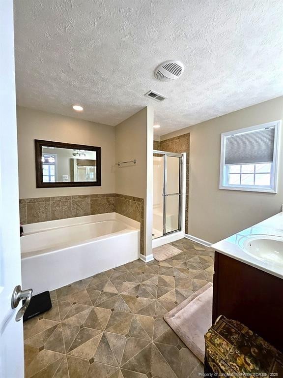 full bath featuring visible vents, vanity, a textured ceiling, a bath, and a shower stall
