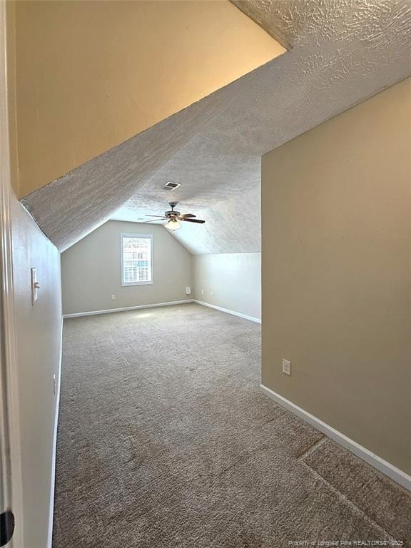 bonus room with ceiling fan, a textured ceiling, baseboards, lofted ceiling, and carpet