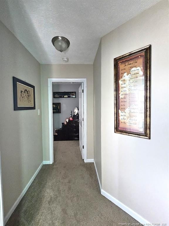corridor featuring baseboards, carpet flooring, and a textured ceiling