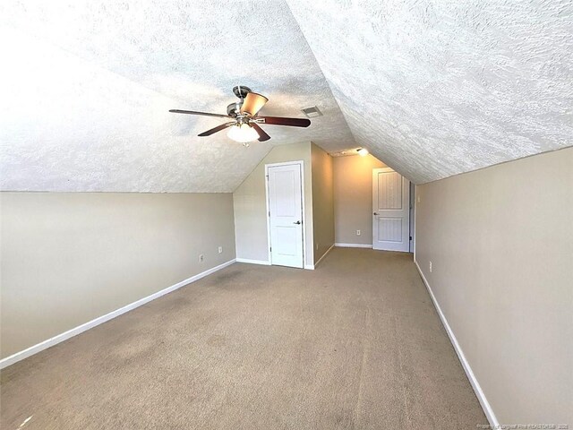 bonus room featuring ceiling fan, a textured ceiling, visible vents, baseboards, and lofted ceiling