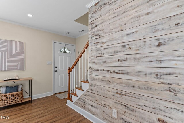 entryway featuring stairs, wood finished floors, baseboards, visible vents, and ornamental molding