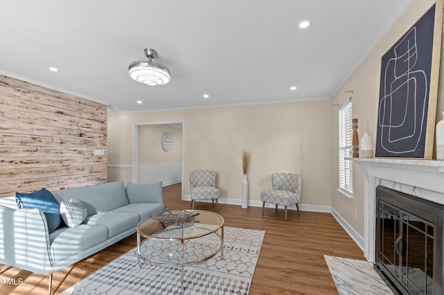 living room featuring crown molding, baseboards, a fireplace, wood finished floors, and recessed lighting