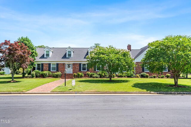 504 W Brocklyn St, Benson, NC 27504 - new england style home featuring brick siding, a front lawn, and a chimney
