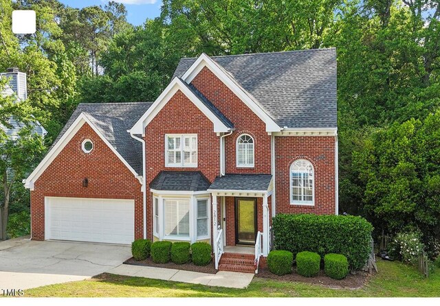traditional-style home with concrete driveway, brick siding, an attached garage, and a shingled roof