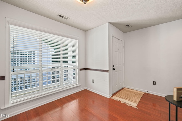 interior space with wood finished floors, baseboards, and visible vents