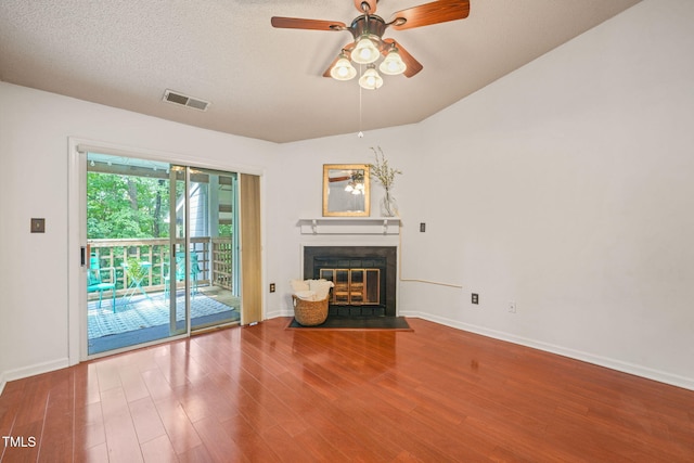 unfurnished living room with a ceiling fan, a fireplace with flush hearth, wood finished floors, baseboards, and visible vents