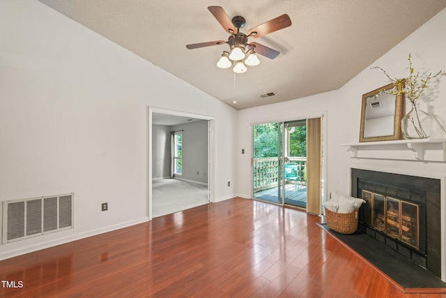 unfurnished living room with visible vents, vaulted ceiling, a glass covered fireplace, and a ceiling fan