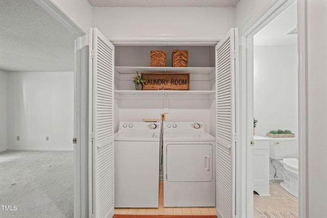 laundry area featuring washing machine and dryer, a textured ceiling, laundry area, and light colored carpet