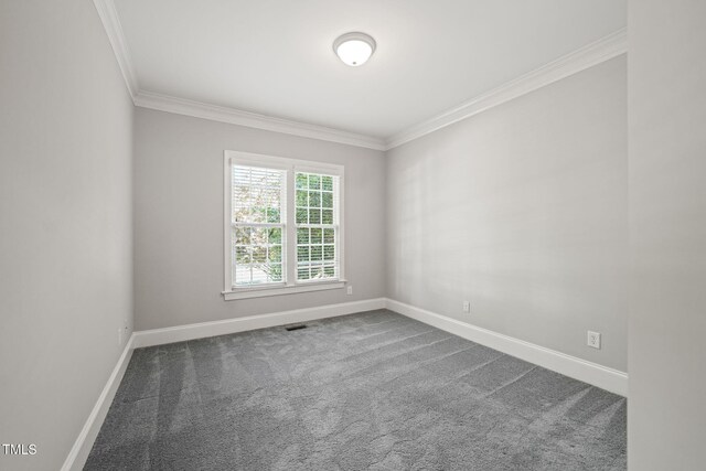 spare room with ornamental molding, dark colored carpet, and baseboards