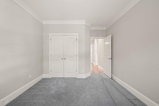 unfurnished bedroom with ornamental molding, carpet flooring, a closet, and baseboards