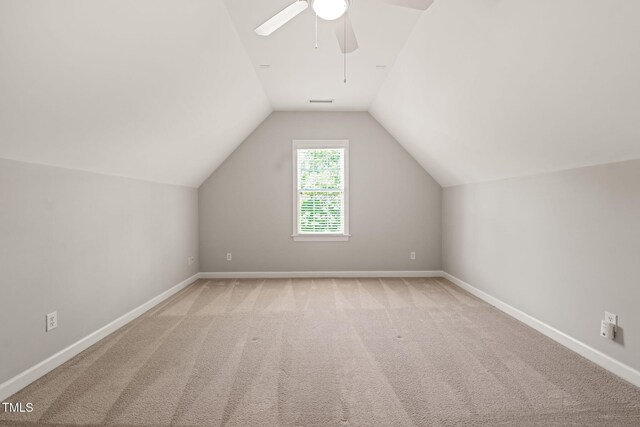 additional living space featuring ceiling fan, vaulted ceiling, baseboards, and light carpet