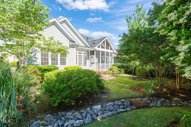 rear view of property with a sunroom and a lawn