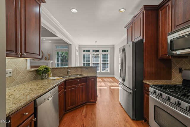 kitchen with stainless steel appliances, a sink, tasteful backsplash, light wood finished floors, and ornamental molding