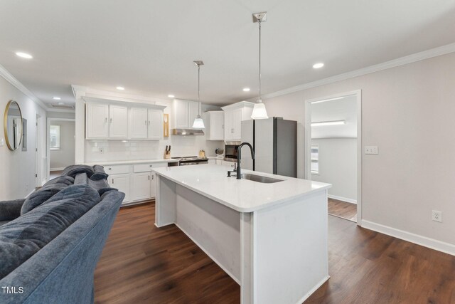 kitchen featuring dark wood-style flooring, ornamental molding, open floor plan, stainless steel appliances, and a sink