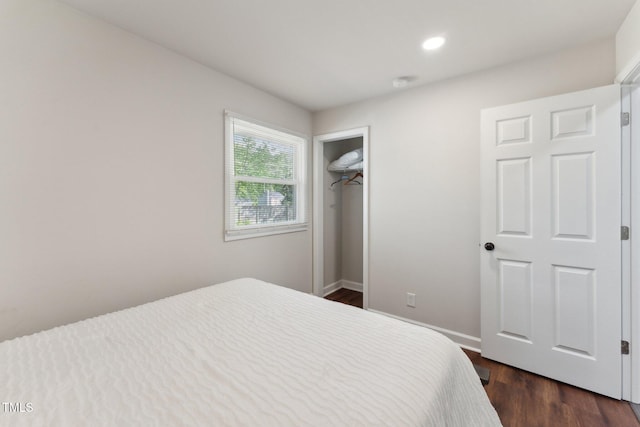 bedroom with dark wood finished floors, a closet, recessed lighting, a walk in closet, and baseboards