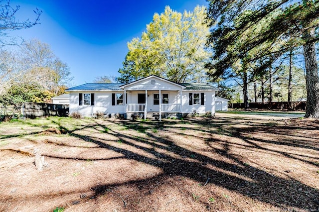 bungalow-style home featuring fence, covered porch, and metal roof