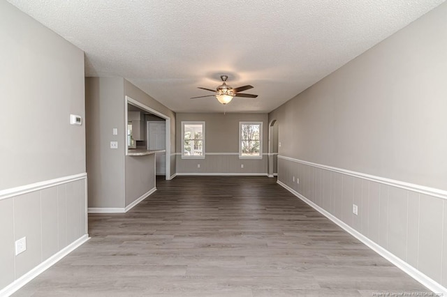 spare room with baseboards, a ceiling fan, a textured ceiling, and wood finished floors