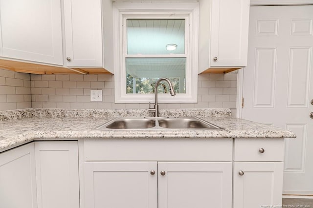 kitchen with white cabinets, decorative backsplash, and a sink