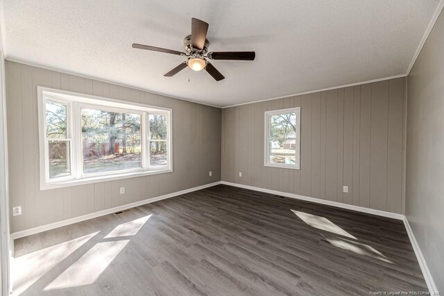 unfurnished room featuring a ceiling fan, dark wood-style flooring, a textured ceiling, baseboards, and ornamental molding