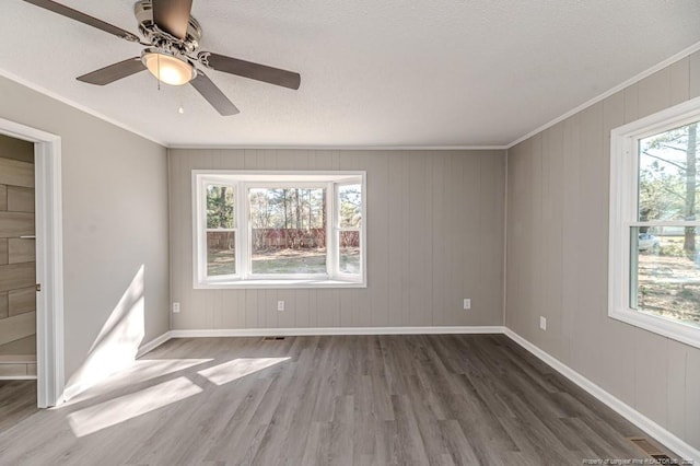 unfurnished bedroom featuring a textured ceiling, visible vents, crown molding, wood finished floors, and baseboards