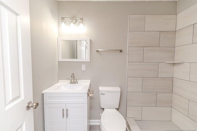 bathroom with vanity, a tile shower, and toilet