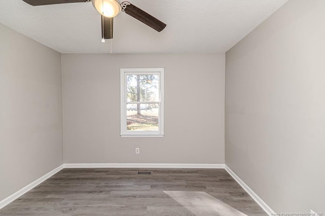 spare room with baseboards, ceiling fan, visible vents, and wood finished floors