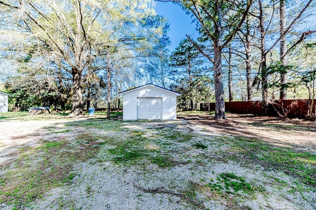 view of yard featuring fence, an outbuilding, and a garage