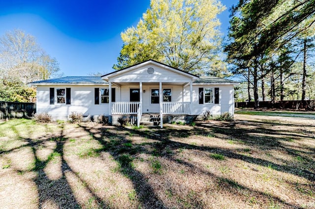 bungalow-style home featuring a porch, fence, and metal roof