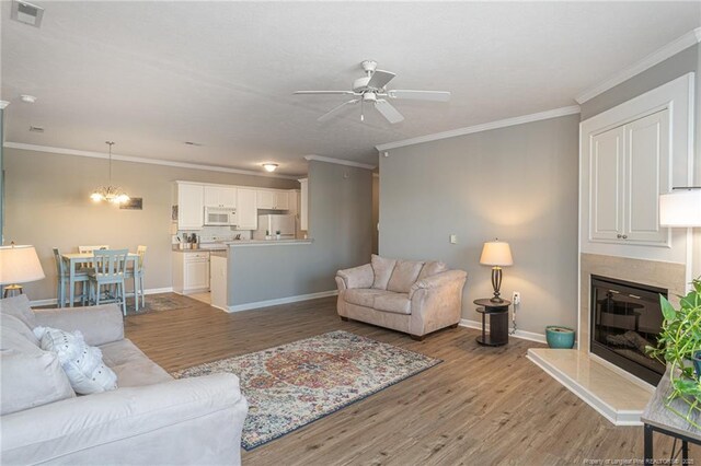 3159 Wisteria Ln Unit 101, Fayetteville, NC 28314 - living room featuring light wood-type flooring, ornamental molding, visible vents, and ceiling fan with notable chandelier