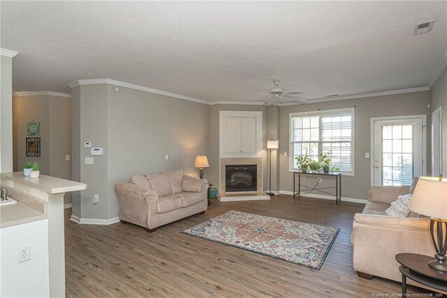 3159 Wisteria Ln Unit 101, Fayetteville, NC 28314 - living room with crown molding, a ceiling fan, wood finished floors, a fireplace with raised hearth, and visible vents