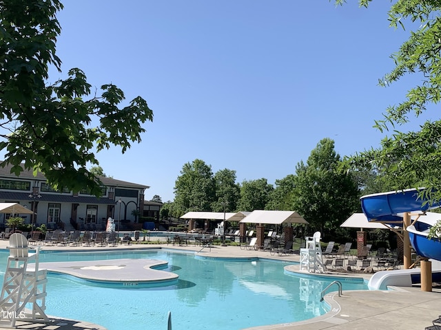 community pool with a water slide and a patio area