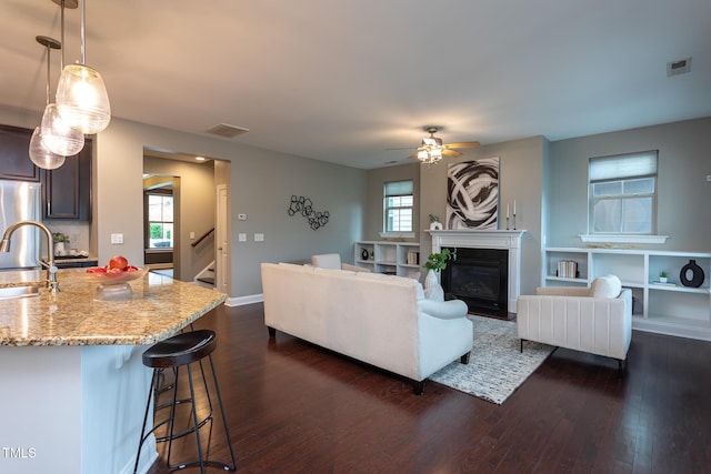 4026 Overcup Oak Ln, Cary, NC 27519 - living room with dark wood finished floors, a ceiling fan, a fireplace with flush hearth, and stairway