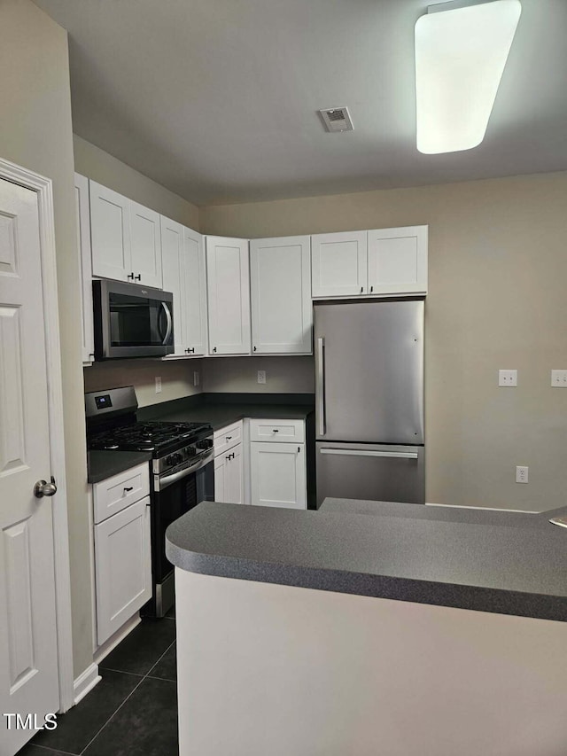 4425 Moss Garden Path, Raleigh, NC 27616 - kitchen with stainless steel appliances, white cabinetry, dark tile patterned flooring, and dark countertops