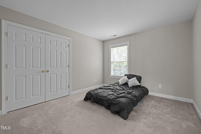carpeted bedroom featuring a closet, visible vents, and baseboards