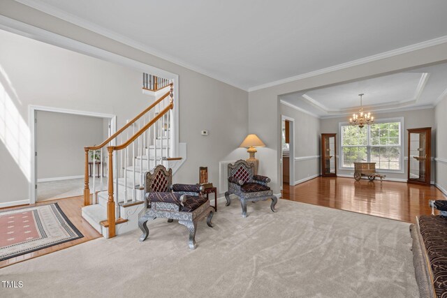sitting room with ornamental molding, an inviting chandelier, carpet floors, and stairs