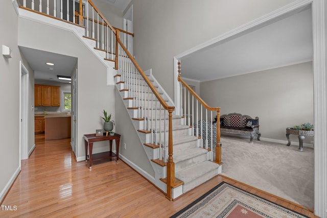 staircase with a high ceiling, wood finished floors, and baseboards