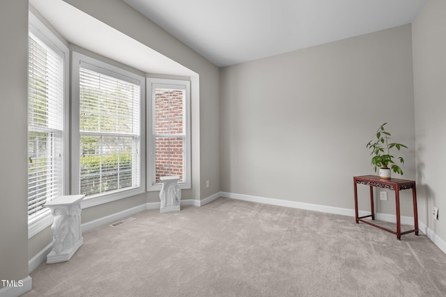 spare room featuring carpet flooring, baseboards, visible vents, and a wealth of natural light
