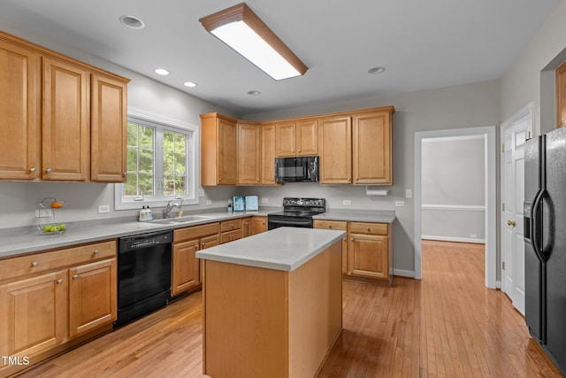 kitchen with light wood-style flooring, light countertops, a kitchen island, black appliances, and a sink