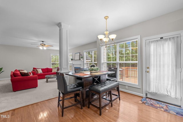 dining room featuring ceiling fan with notable chandelier, decorative columns, baseboards, and light wood finished floors