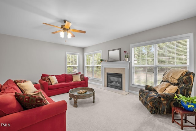 carpeted living room with a wealth of natural light, a glass covered fireplace, and a ceiling fan