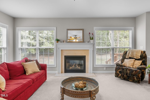 living room with baseboards, carpet flooring, and a glass covered fireplace