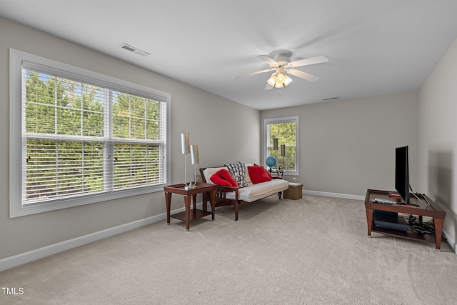 living area featuring visible vents, baseboards, a ceiling fan, and light carpet