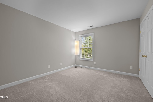 carpeted spare room featuring visible vents and baseboards