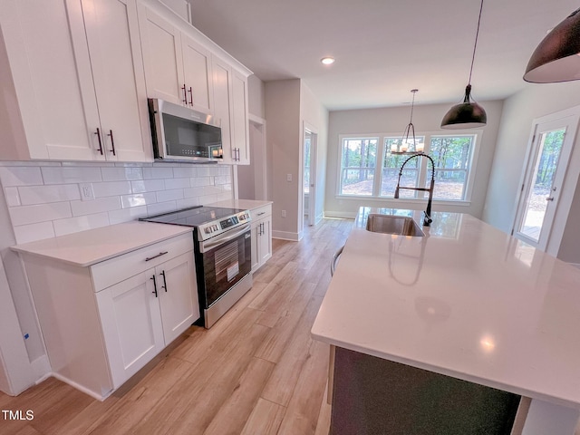 217 Duncan Creek Rd # 124, Lillington, NC 27546 - kitchen featuring stainless steel appliances, a sink, light countertops, tasteful backsplash, and light wood-style floors