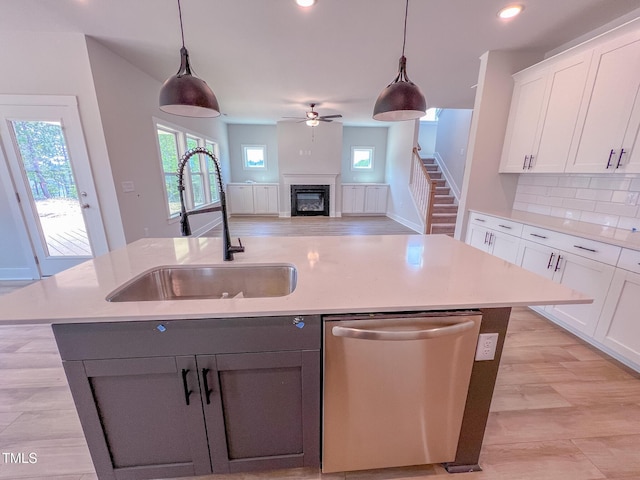 217 Duncan Creek Rd # 124, Lillington, NC 27546 - kitchen featuring dishwasher, a kitchen island with sink, a glass covered fireplace, a sink, and a ceiling fan