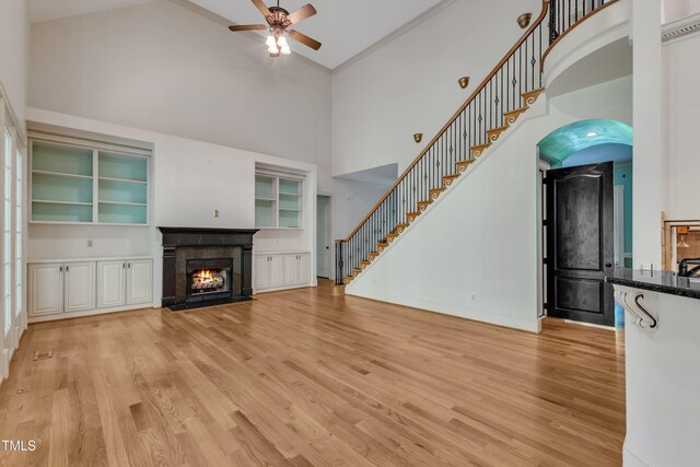 85 Christenbury Ln, Clayton, NC 27527 - unfurnished living room featuring ceiling fan, a high ceiling, stairway, light wood-type flooring, and a fireplace with flush hearth