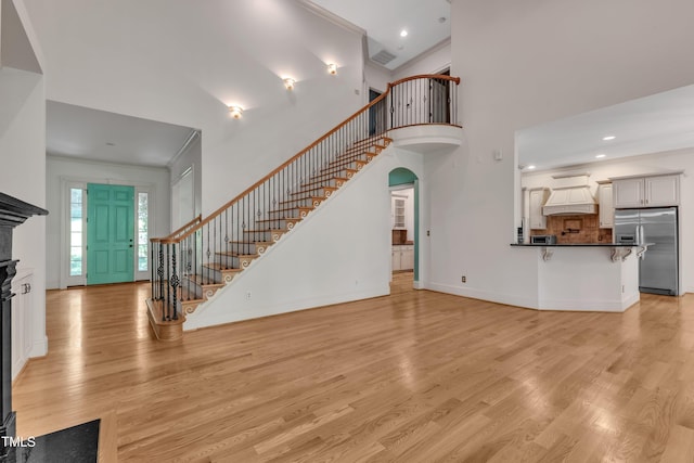 85 Christenbury Ln, Clayton, NC 27527 - unfurnished living room with crown molding, light wood-style flooring, stairs, and a high ceiling